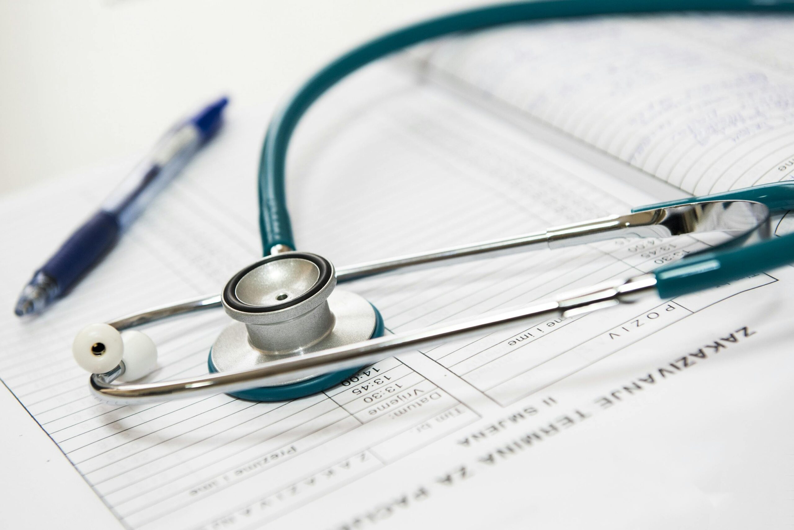 Stethoscope and pen on top of a stack of papers.